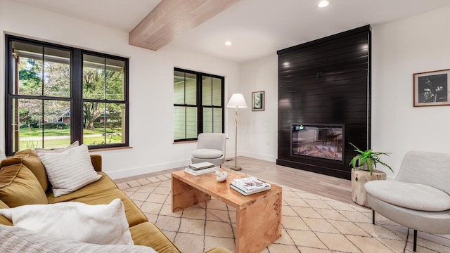 living room with a large fireplace, light hardwood / wood-style floors, and beam ceiling