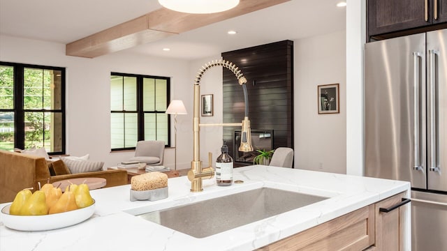 kitchen with a wood stove, light stone countertops, sink, high end refrigerator, and light brown cabinetry