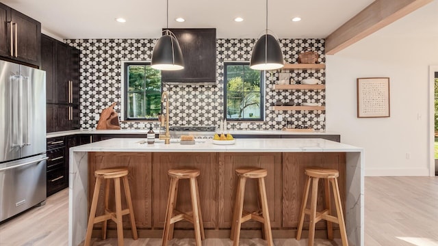 kitchen featuring a kitchen breakfast bar, light stone countertops, high end fridge, and an island with sink