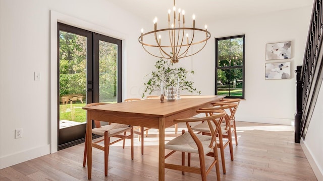 dining space featuring light wood-type flooring, french doors, and a chandelier