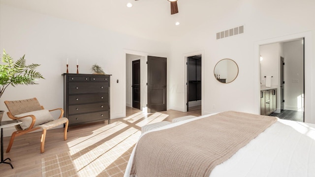 bedroom featuring ceiling fan, light wood-type flooring, and ensuite bath