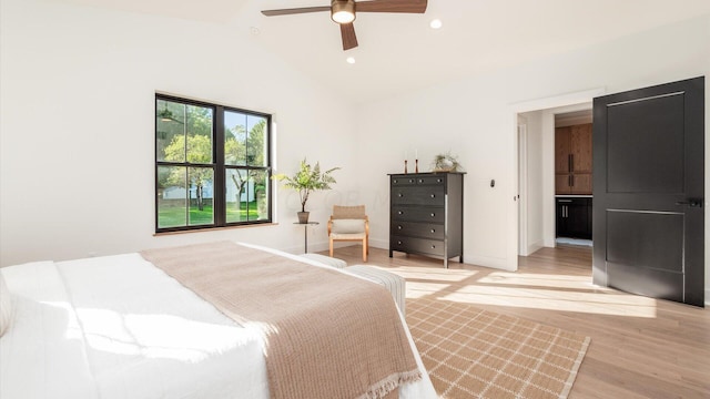 bedroom featuring ceiling fan, light wood-type flooring, ensuite bathroom, and lofted ceiling