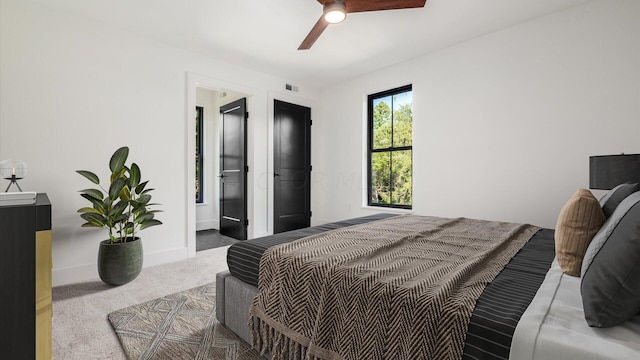 carpeted bedroom with ensuite bathroom and ceiling fan