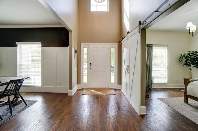 entryway featuring plenty of natural light, a barn door, dark hardwood / wood-style floors, and a high ceiling