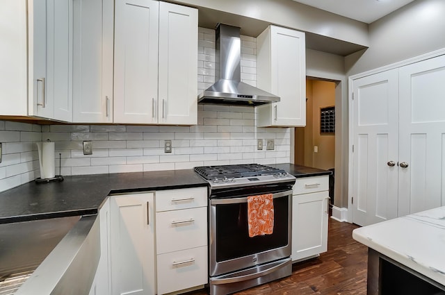 kitchen featuring stainless steel gas range oven, white cabinets, dark hardwood / wood-style floors, and wall chimney range hood