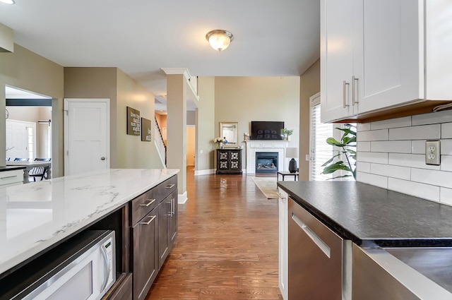 kitchen with backsplash, white cabinetry, light stone counters, and dark hardwood / wood-style floors