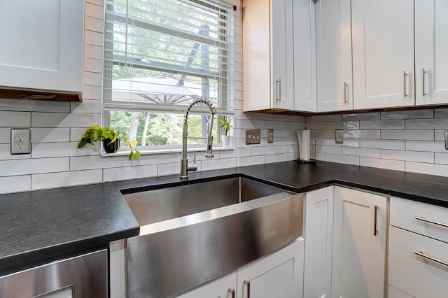 kitchen featuring decorative backsplash, white cabinetry, and sink