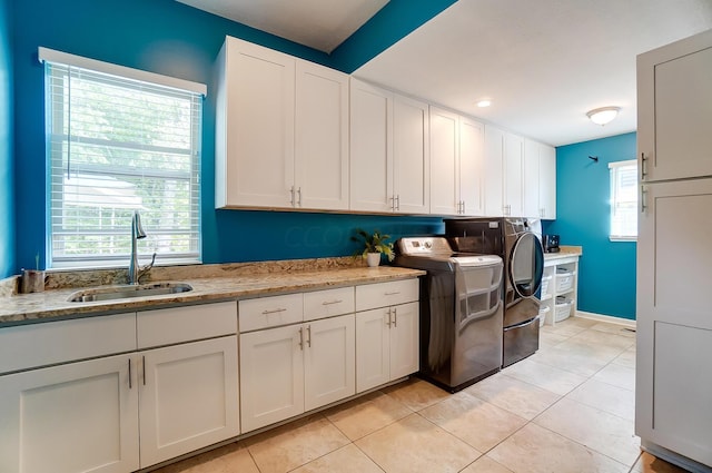 kitchen with light stone countertops, white cabinetry, sink, and washing machine and clothes dryer