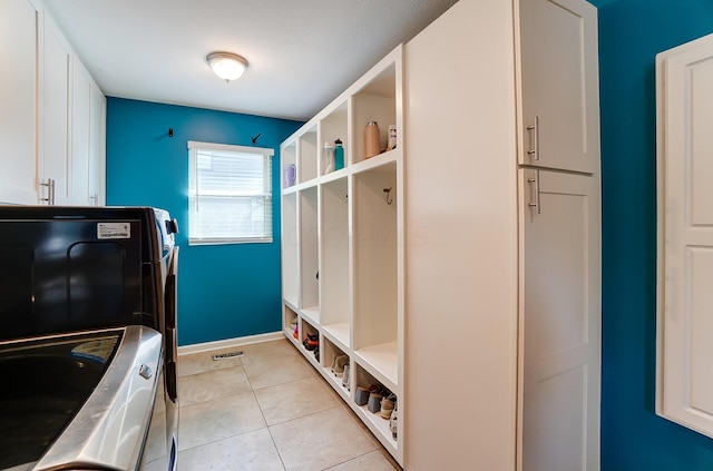 washroom with washing machine and clothes dryer, light tile patterned floors, and cabinets