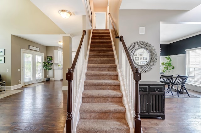 stairs with french doors, a towering ceiling, hardwood / wood-style flooring, and a wealth of natural light