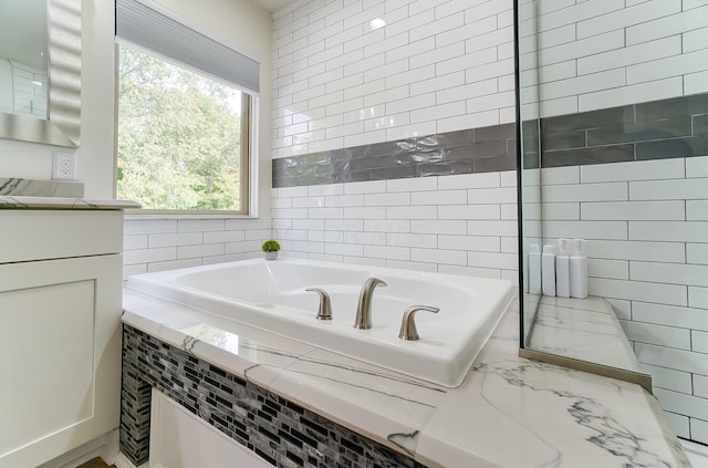 bathroom with a relaxing tiled tub and vanity