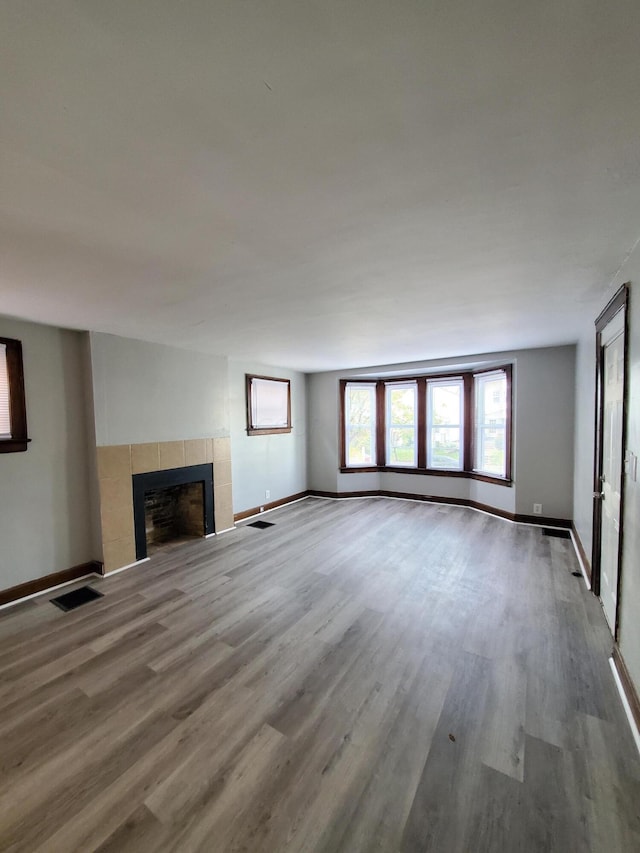 unfurnished living room featuring a tile fireplace and wood-type flooring