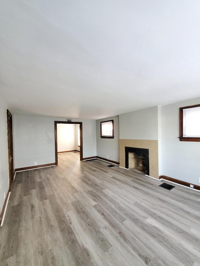 unfurnished living room featuring a fireplace, a wealth of natural light, and light hardwood / wood-style flooring