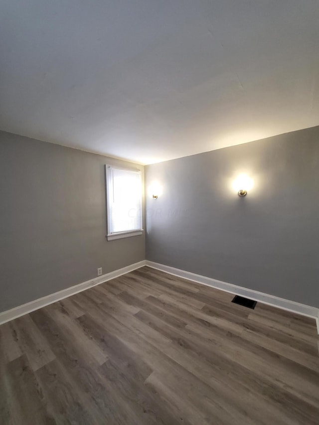 unfurnished room with dark hardwood / wood-style flooring