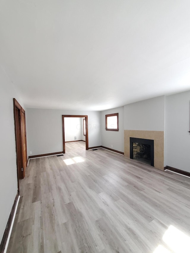 unfurnished living room featuring a fireplace and light hardwood / wood-style floors