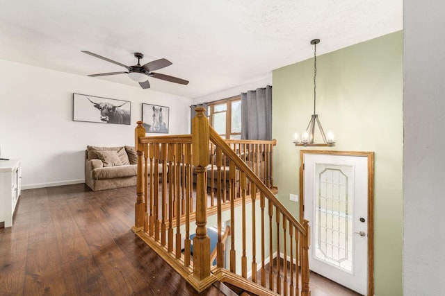 staircase featuring ceiling fan with notable chandelier and hardwood / wood-style flooring