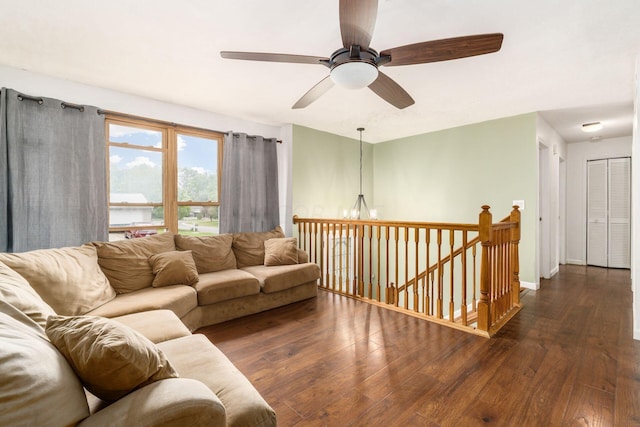 living room with ceiling fan with notable chandelier and dark hardwood / wood-style flooring