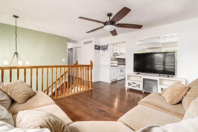 living room featuring dark hardwood / wood-style flooring and ceiling fan with notable chandelier