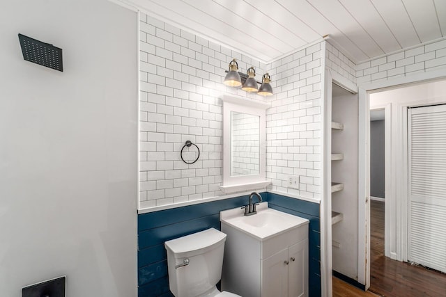 bathroom with hardwood / wood-style floors, vanity, toilet, and tile walls