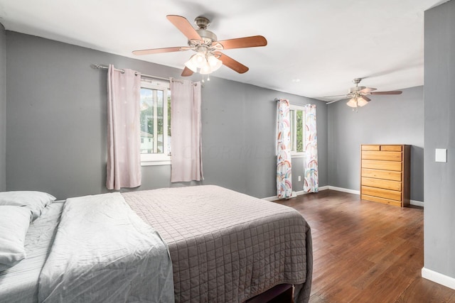 bedroom with multiple windows, ceiling fan, and dark wood-type flooring