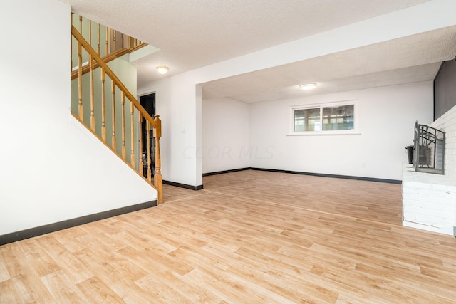 unfurnished living room with a textured ceiling and light wood-type flooring