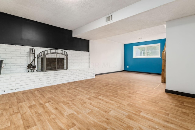 unfurnished living room with a fireplace, a textured ceiling, and light wood-type flooring