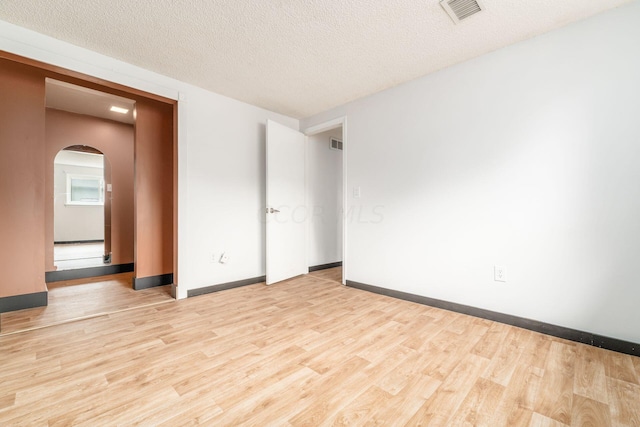 spare room with light wood-type flooring and a textured ceiling