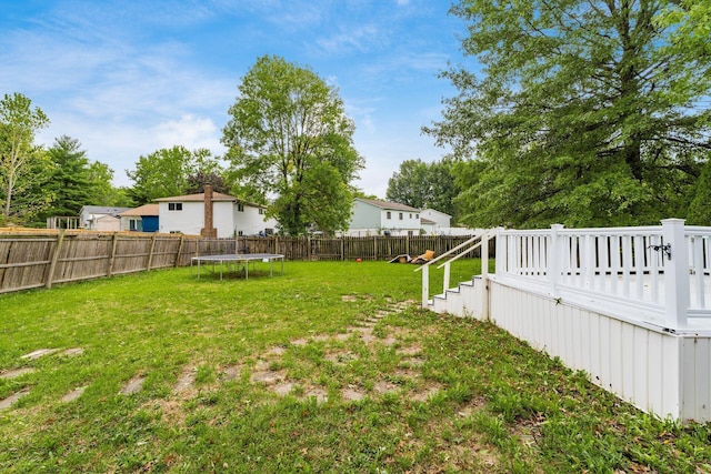 view of yard with a wooden deck and a trampoline