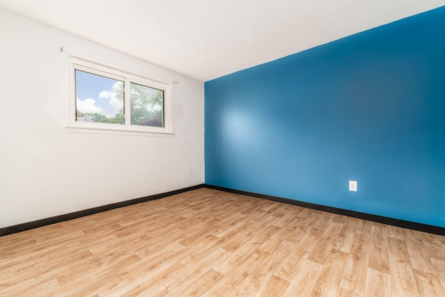 spare room featuring light hardwood / wood-style flooring and a textured ceiling