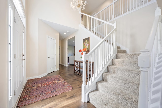 foyer entrance featuring dark hardwood / wood-style floors, a towering ceiling, and a chandelier