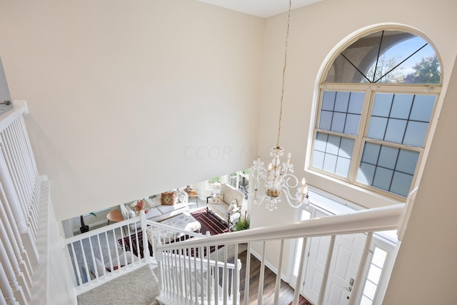 staircase with hardwood / wood-style floors, a high ceiling, and an inviting chandelier