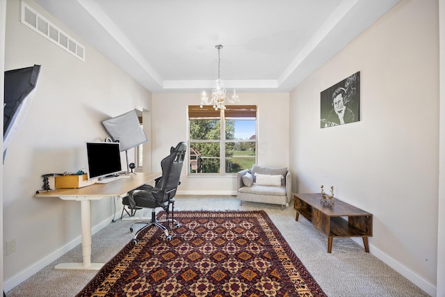 carpeted office space featuring a tray ceiling and an inviting chandelier