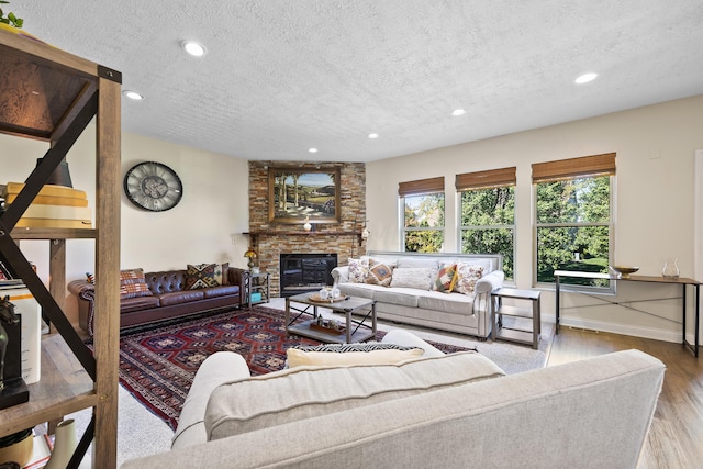 living room with a fireplace, a textured ceiling, and light hardwood / wood-style flooring