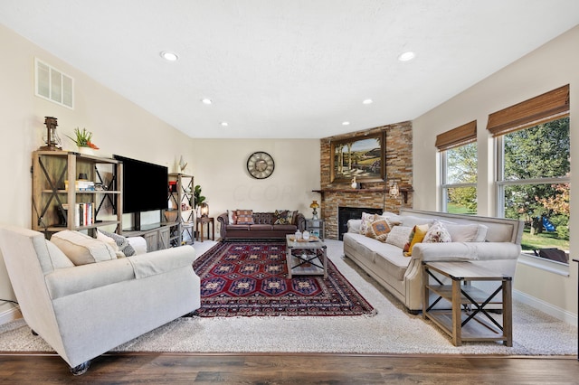 living room with a stone fireplace and dark hardwood / wood-style floors