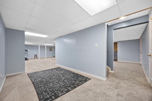 basement with a paneled ceiling and light colored carpet