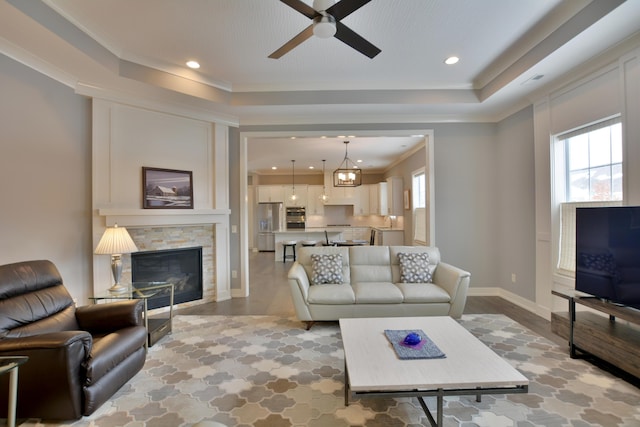 living room with ceiling fan with notable chandelier, a stone fireplace, plenty of natural light, and hardwood / wood-style flooring