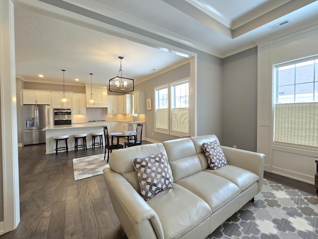 living room with sink, a chandelier, crown molding, and dark hardwood / wood-style floors