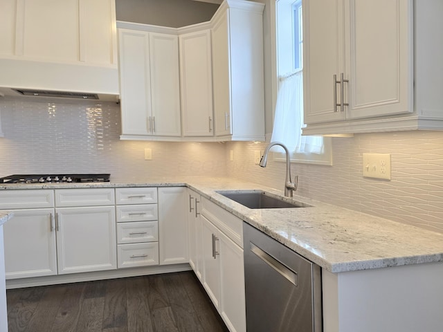 kitchen featuring stainless steel dishwasher, white cabinetry, sink, and backsplash