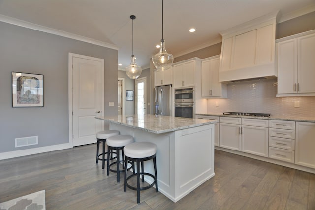 kitchen featuring stainless steel appliances, white cabinetry, a center island, and hanging light fixtures