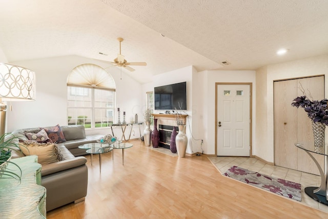 living room featuring vaulted ceiling, ceiling fan, a textured ceiling, and hardwood / wood-style flooring