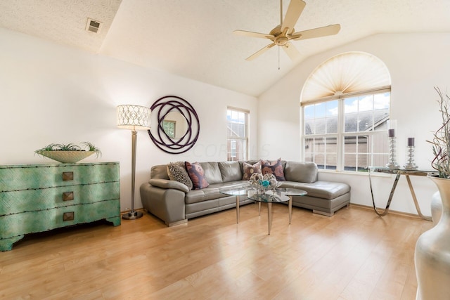 living room with wood-type flooring, a textured ceiling, vaulted ceiling, and ceiling fan