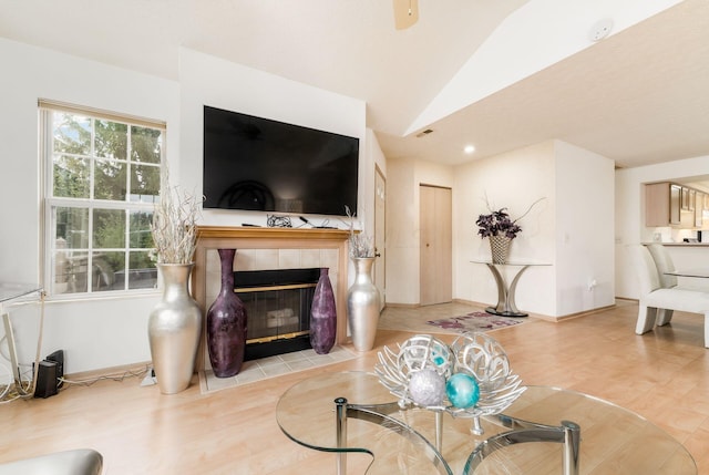 living room featuring a fireplace, vaulted ceiling, and light wood-type flooring