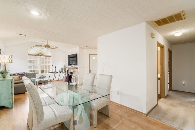 dining room with vaulted ceiling, ceiling fan, a textured ceiling, and light wood-type flooring