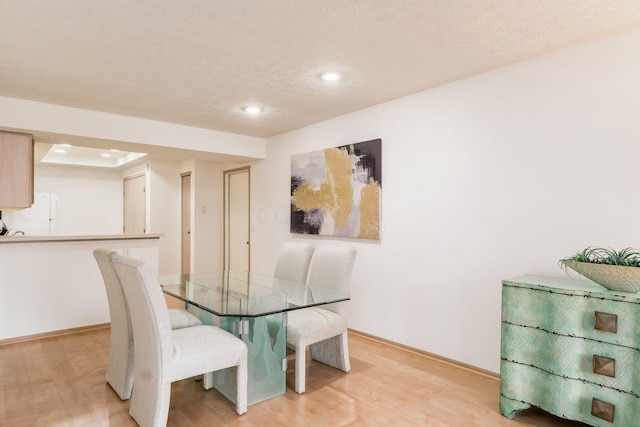 dining area with light hardwood / wood-style floors and a textured ceiling