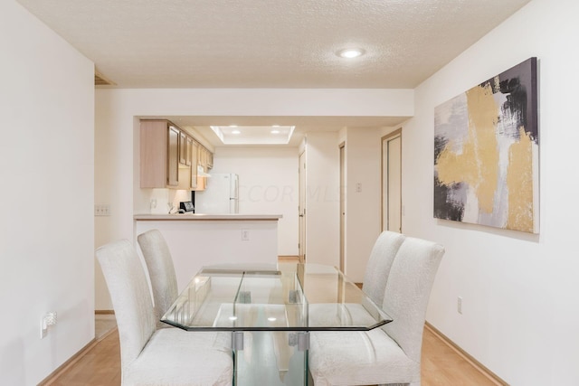 dining area with light wood-type flooring and a textured ceiling