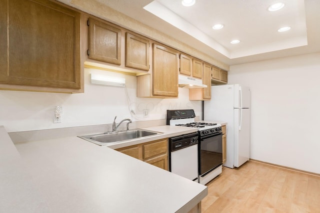 kitchen featuring a raised ceiling, sink, white appliances, and light hardwood / wood-style flooring