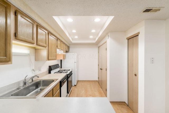 kitchen featuring sink, light hardwood / wood-style floors, a textured ceiling, white appliances, and a tray ceiling