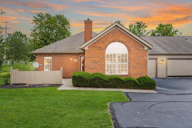 ranch-style house featuring a garage and a yard