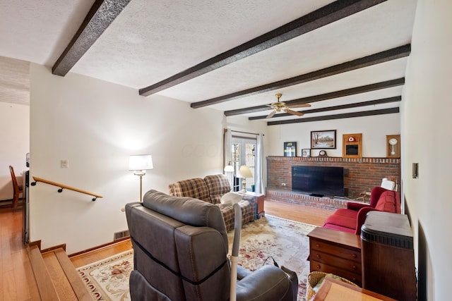 living room with beam ceiling, a textured ceiling, and light hardwood / wood-style flooring