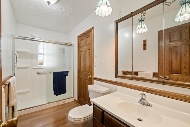 bathroom with vanity, hardwood / wood-style flooring, toilet, a textured ceiling, and an enclosed shower